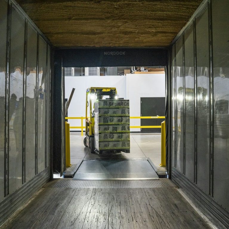 Forklift transporting stacks of boxes through a loading dock.