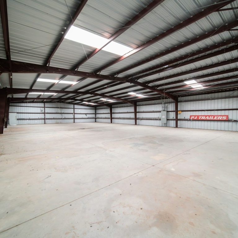 Spacious industrial warehouse interior with metal beams and concrete floor.